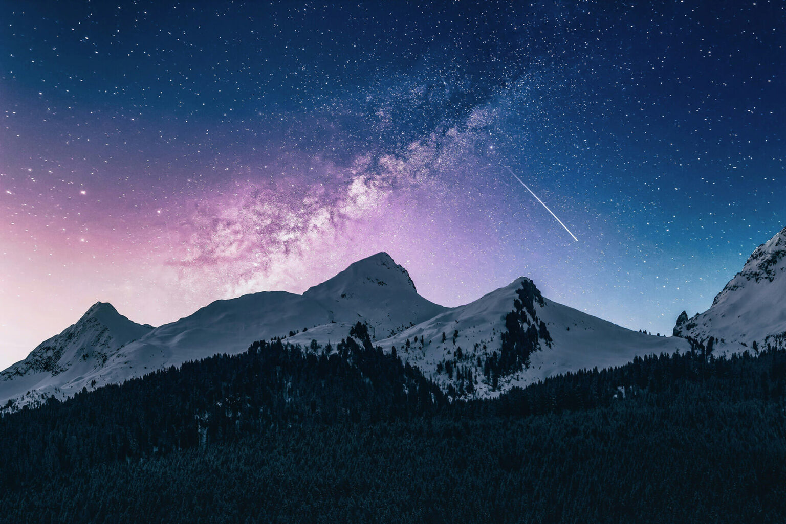 Mountain range at night time with a colourful night sky behind